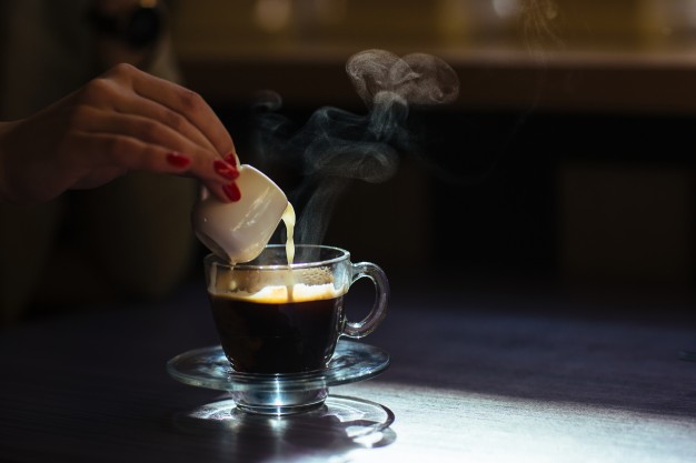 woman-pouring-milk-into-her-coffee_1153-545