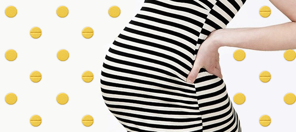 A pregnant woman in stripes with Folic Acid pills in the background