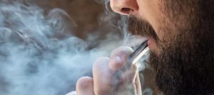 man with beard vaping smoke